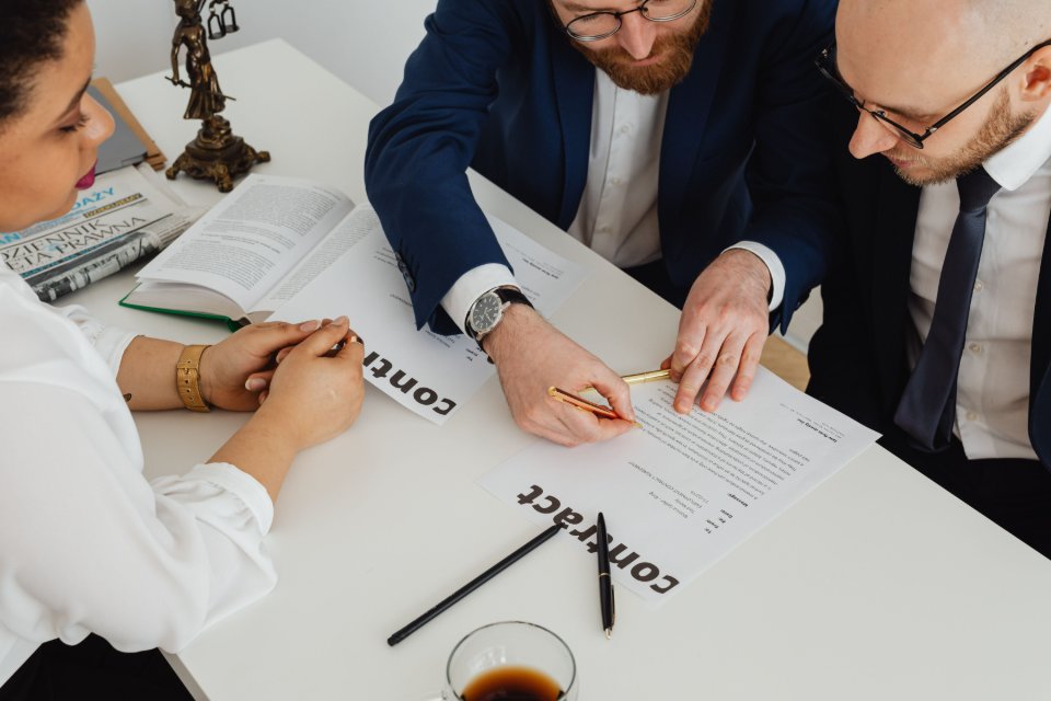 Professionals comparing and reviewing contract documents at a desk.