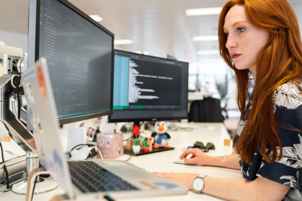 A software engineer working at a workstation with code on the monitors.