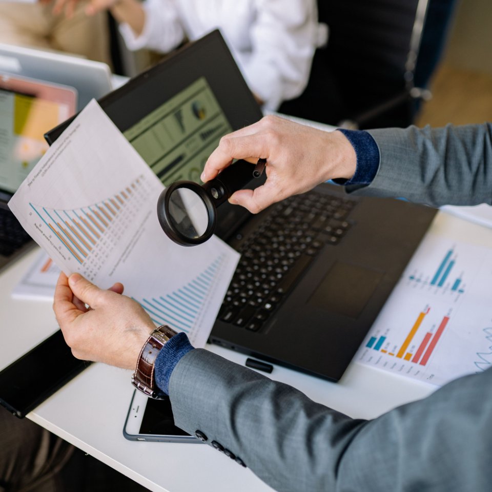 A professional examining printed data beside a laptop.