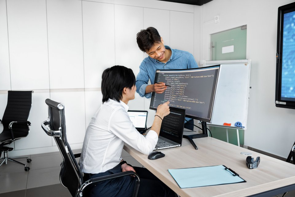 Two technical colleagues collaborating at a workstation with computers.
