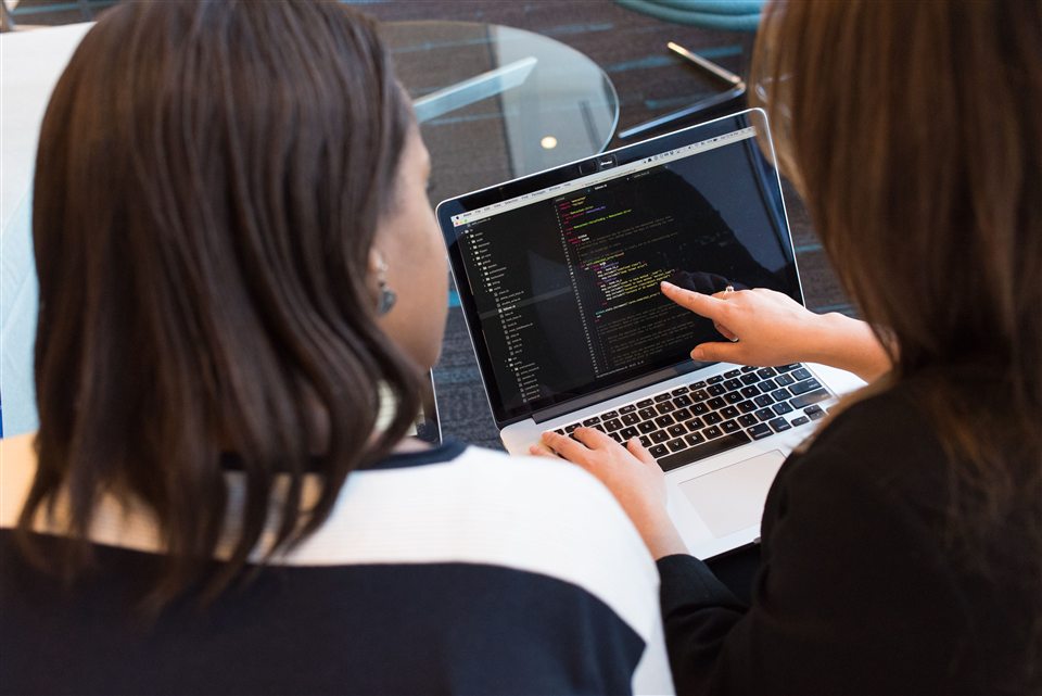 Two developers reviewing code on a laptop.