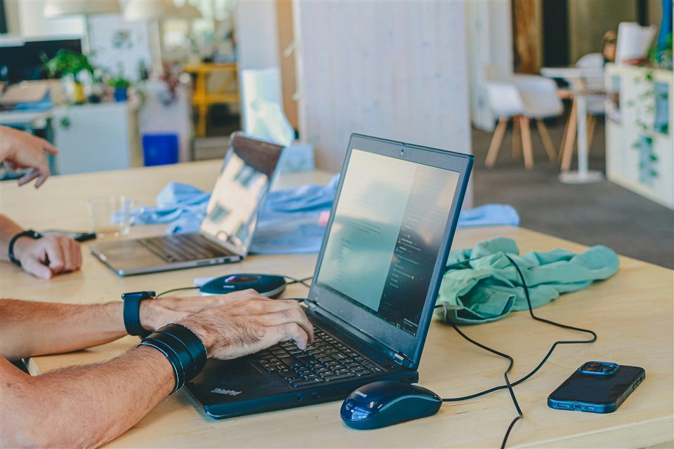 Hands working on laptops at a shared development table.